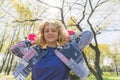 Horizontal outdoor shot of a pretty young joyful girl with blonde hair standing in the sun looking at a camera holding a Royalty Free Stock Photo