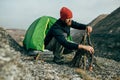 Horizontal outdoors image of young hiker male prepare brunches for bonfire in mountains.