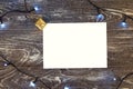 Horizontal paper blank with christmas lights frame. Flat lay. New year card gift. Gold presents. On grey wooden background. Top Royalty Free Stock Photo