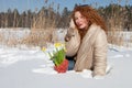 Charismatic pretty woman sitting in snowdrift and holding her coat collar