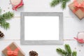 Horizontal photo frame surrounded with Christmas New Year gifts, tree branches and decorations.