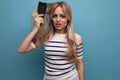 horizontal photo of a sad upset blond young woman with a hairbrush in her hands on a blue background Royalty Free Stock Photo