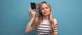 horizontal photo of a sad upset blond young woman with a hairbrush in her hands on a blue background Royalty Free Stock Photo