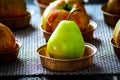 One greenish pear of small size on the background of apples Royalty Free Stock Photo