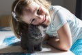 Little girl leaning over her adorable blue-eyed tiny grey kitten