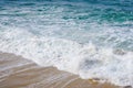 Turquoise ocean water with small white foam waves gently crashing into golden sand beach Royalty Free Stock Photo