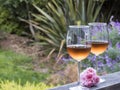 A horizontal photo of two glasses of rosÃÂ© sitting on an outdoor railing