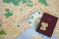 Undefined red passport with banknotes and euro coins money on top of a local map. Concept for travel budget planning. Royalty Free Stock Photo