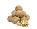 Walnut kernels in front of pyramid of walnut shells on white background.