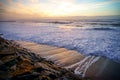 White foam waves crashing into mossy rocks, with a beautiful autumn sunset. Inspirational background with copy space.