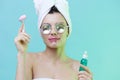 Horizontal photo, a woman with gorgeous skin on a blue background in a towel on her head and body and luxurious glasses