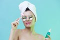 Horizontal photo, a woman with gorgeous skin on a blue background in a towel on her head and body and luxurious glasses