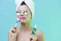 Horizontal photo, a woman with gorgeous skin on a blue background in a towel on her head and body and luxurious glasses