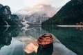 Horizontal photo. Wooden boat on the crystal lake with majestic mountain behind. Reflection in the water