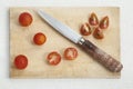 Wooden cutting board with knife and cut red cherry tomatoes. Royalty Free Stock Photo