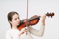 A girl with a bow playing the violin and looking at strings over white background Royalty Free Stock Photo