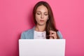 Horizontal picture of smart charming lovely young lady posing isolated over pink background in studio, holding eyeglasses in hand Royalty Free Stock Photo