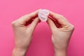 Horizontal picture of unknown hands holding rubber menstrual cup in both hands, twisting it, being ready to use, reusable product