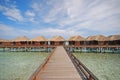 Blue sky horizontal picturesque wooden bridge walkway leading to a Row of Luxury Overwater Villa at a resort island, Maldives