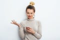 Horizontal portrait of displeased woman has indignant expression while holding smartphone, frowns eyebrows, can`t understand