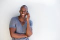 Happy black guy leaning against white wall talking on cell phone Royalty Free Stock Photo