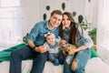 The horizontal portrait of the happy family sitting on the bed and holding the baby and the rabbit. Royalty Free Stock Photo