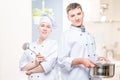 Horizontal portrait of a pair of cooks with a pan and a ladle