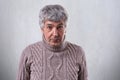 A horizontal portrait of senior handsome man standing against white wall wearing sweater looking with astonishment into camera. Pe