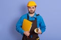 Horizontal portrait of serious good looking young man holding projects and documents in both hands, looking directly at camera,