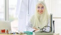 Horizontal portrait shot of an attractive smiling adult Muslim woman wearing cream hijab, stethoscope, and eyeglasses looking at Royalty Free Stock Photo