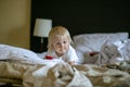 Horizontal portrait of a two year old baby girl resting on a bed in a hotel room