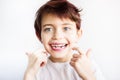 Horizontal portrait of 7 years old smiling child in white t-shirt flossing his teeth on white background isolated. Healthcare and Royalty Free Stock Photo