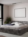 Horizontal poster mockup with black frame in modern style bedroom interior with gray bed, plant and empty beige wall background. Royalty Free Stock Photo