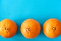 Horizontal row of three blood oranges on blue background