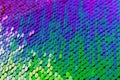 Horizontal shiny textured background with iridescent round multicolored sequins sewn on the fabric like scales