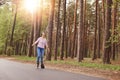 Horizontal shot of active slender cute young female rollerblading alone, listening to music, riding alone road, being in forest,