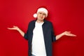 Horizontal shot of attractive man with puzzled expression spreads hands with confused look, wears christmas hat feels Royalty Free Stock Photo