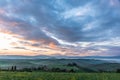 Horizontal shot of a beautiful green field with buildings and green trees under colorful evening sky Royalty Free Stock Photo