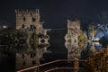 Horizontal shot of beautiful Italian castles connected with a bridge over the lake at nighttime