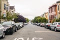 Horizontal shot of a beautiful street with trees, parked cars and classic San Francisco houses on both sides, California - United