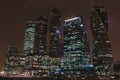 Horizontal shot of big city high glass buildings of different shape, with lighted windows at night, on dark brown sky Royalty Free Stock Photo