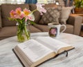 Horizontal shot of a book set on a coffee table with a mug and flowers on a brown couch background Royalty Free Stock Photo