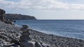 Solitary pebble beach with one rock cairn in a sunny morning, at Playa de San Juan, Tenerife, Canary Islands, Spain