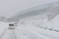 White Passenger Van Driving Down a Snowy Highway Under a Long Concrete Bridge in Winter Royalty Free Stock Photo