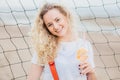 Horizontal shot of cheerful glad blonde female dressed in casual clothes, holds fresh orange cocktail, smiles positively, poses ag