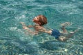 Child boy learning to swim in clear transparent sea. Royalty Free Stock Photo