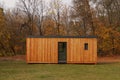 Horizontal shot of a contemporary, rectangular, cedar sided modular home tiny house set in a field with autumn foliage in the Royalty Free Stock Photo