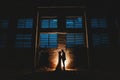 Horizontal shot of a couple` standing near a light source in silhouette in an abandoned building