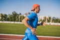 Horizontal shot determinated young Caucasian male athletic running alone along a race track in stadium while out training on a Royalty Free Stock Photo