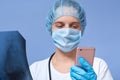 Horizontal shot of female doctor talking on phone in hospital or office clinic, examining spinal scans, call to her colleague to Royalty Free Stock Photo